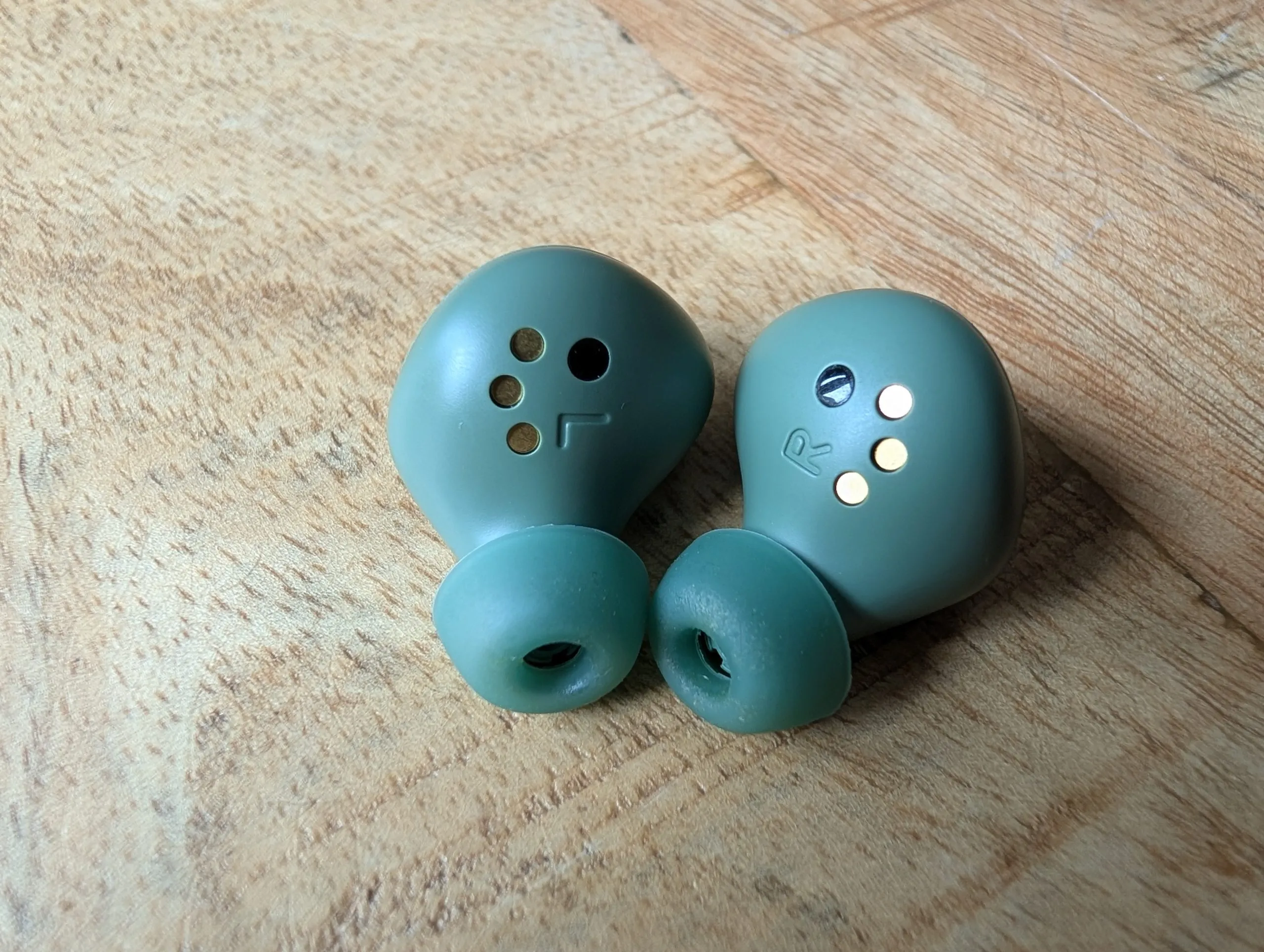 Detalle de los auriculares en verde sobre una superficie de madera
