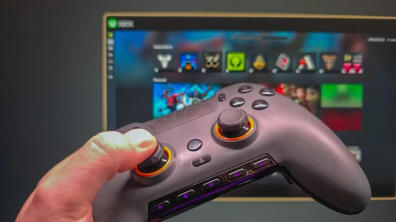 Mando sujeto con la mano y el modo Xbox activo al fondo