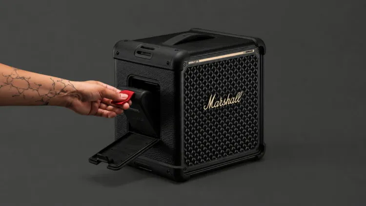 Una mano extrae la batería LFP reemplazable del compartimento lateral del Marshall Bromley 150