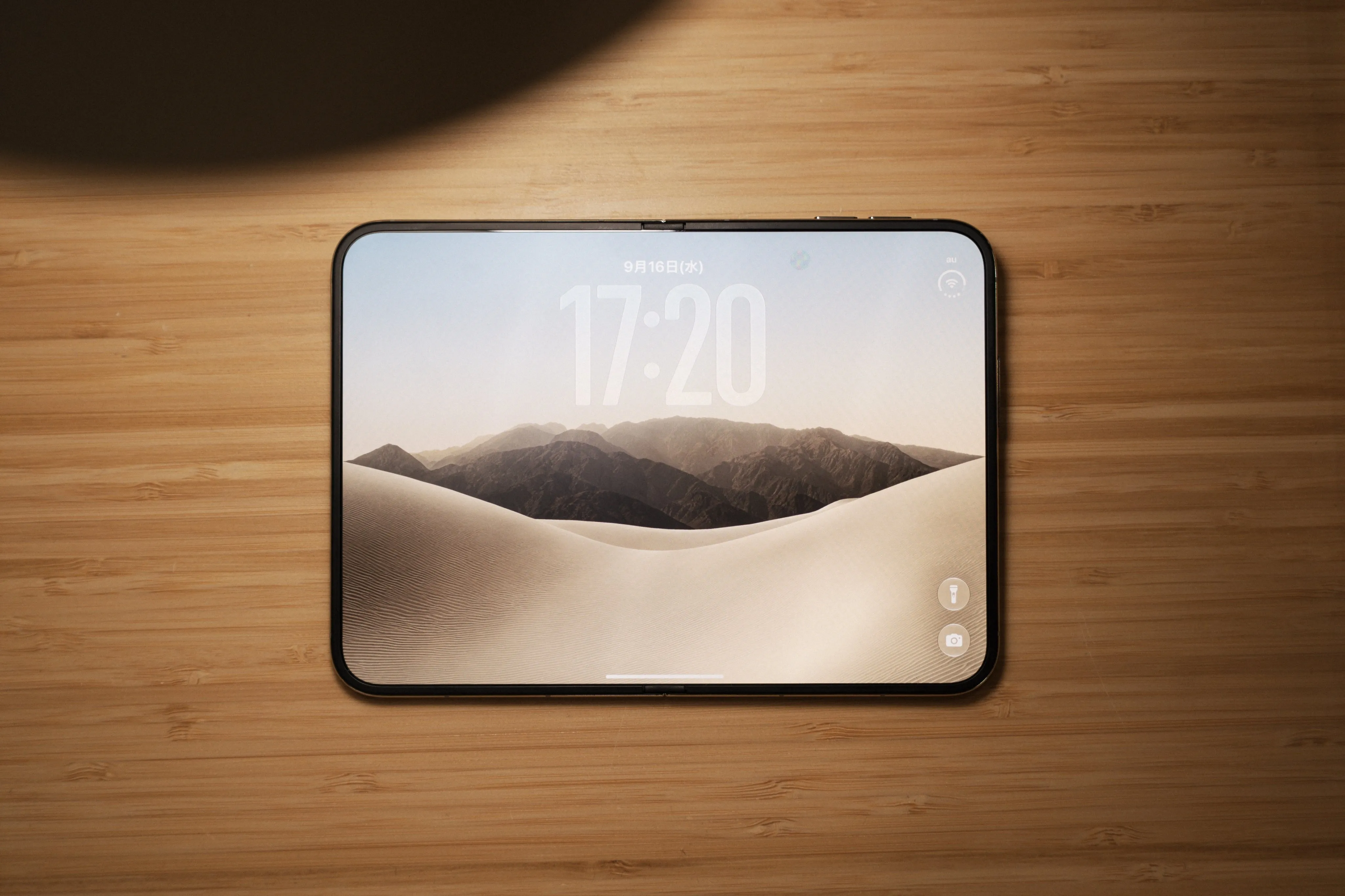 El iPhone Duo desplegado sobre una mesa de madera, con la pantalla de bloqueo activa