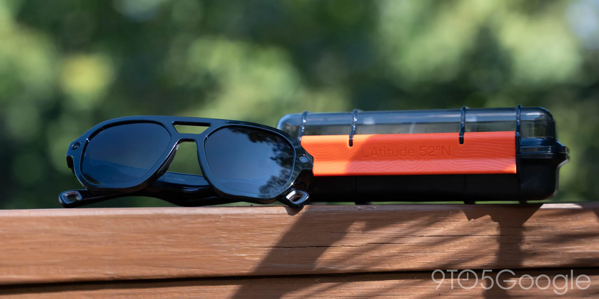 Las gafas Latitude 52°N Berlin plegadas junto a su funda cilíndrica naranja y negra