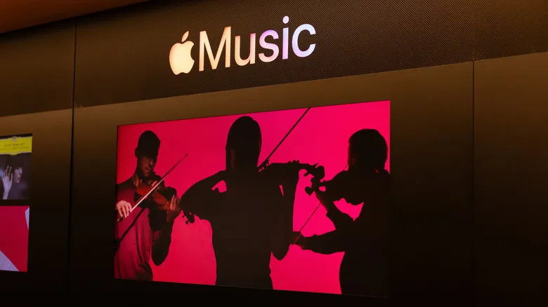 Pantalla de Apple Music con fondo rojo en la que aparecen músicos tocando el violín