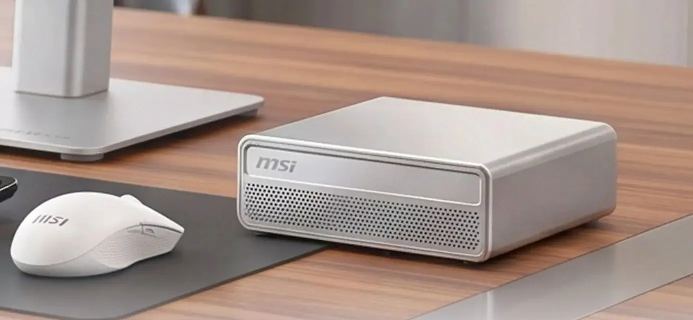 Mini PC MSI en color plateado junto a un ratón inalámbrico blanco sobre un escritorio de madera