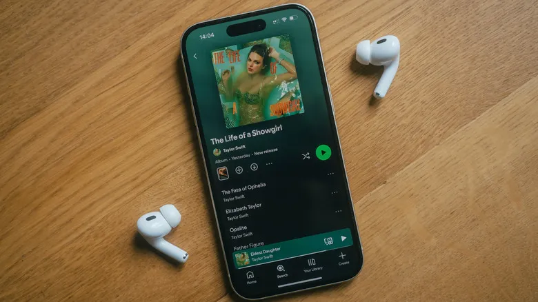 iPhone con dos AirPods mostrando un álbum en Spotify