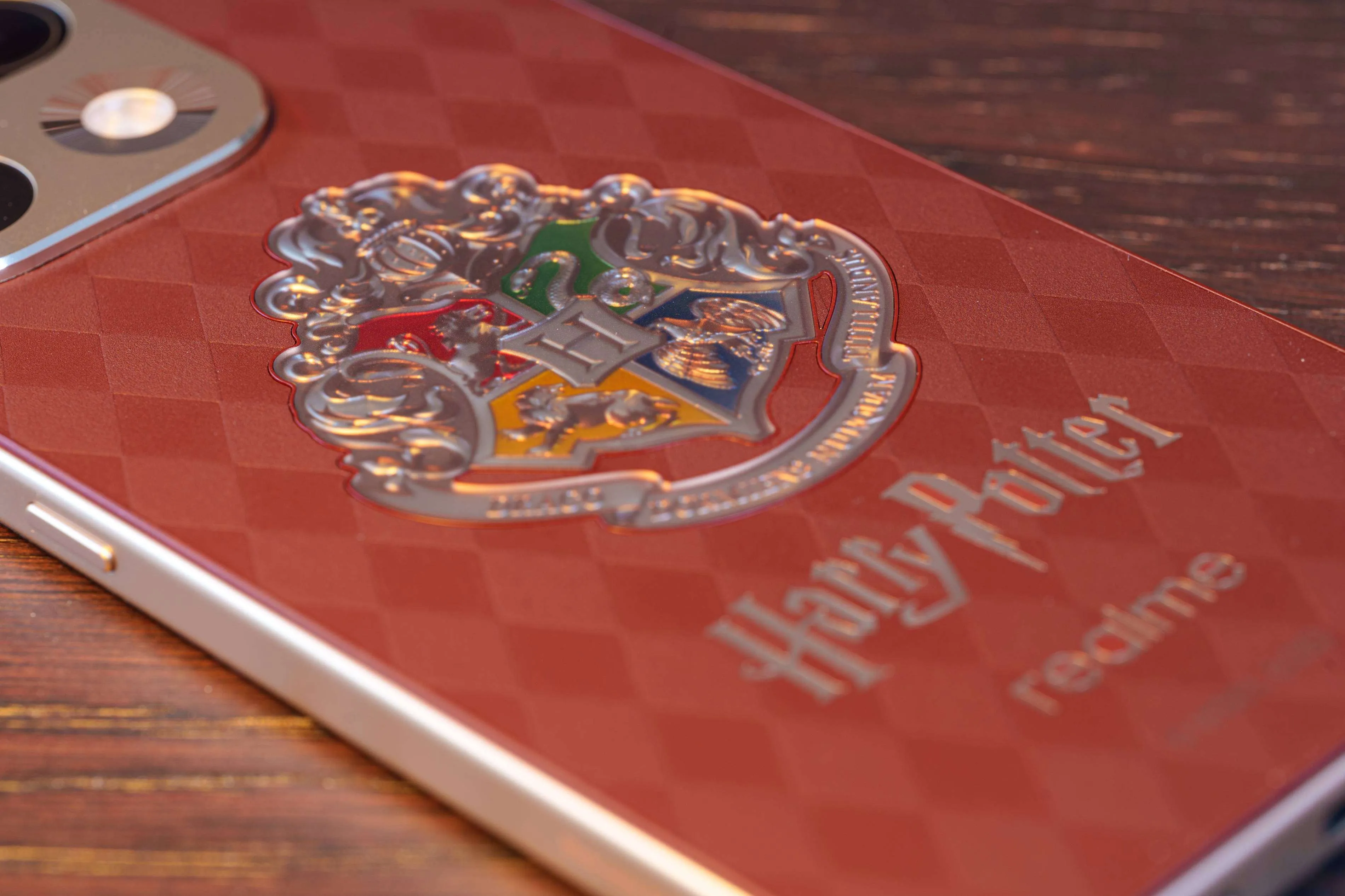 Primer plano del panel trasero con textura de cuero, el patrón de rombos y los logotipos de Harry Potter y realme
