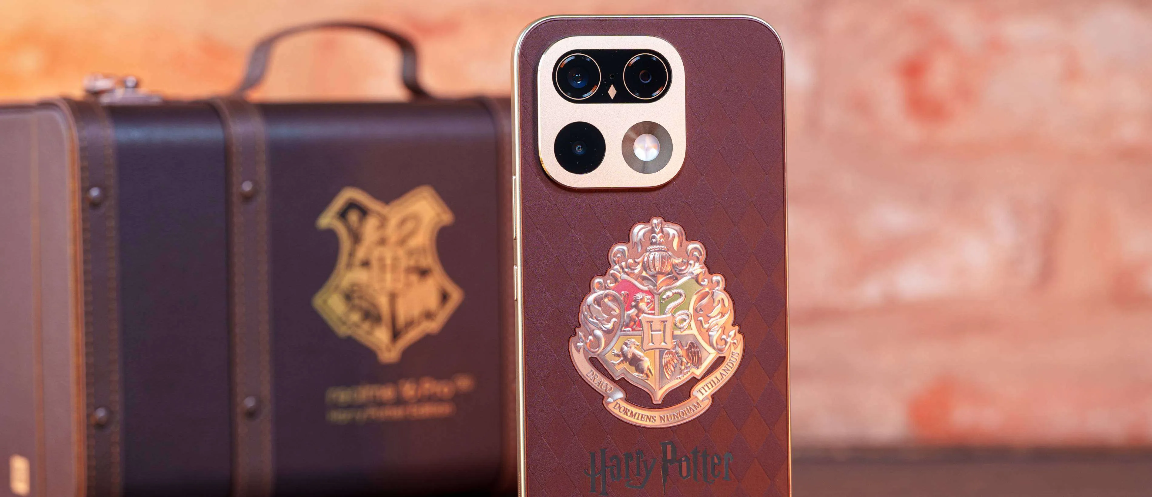 La Realme 16 Pro Harry Potter Edition de pie junto a la maleta de Hogwarts sobre una mesa