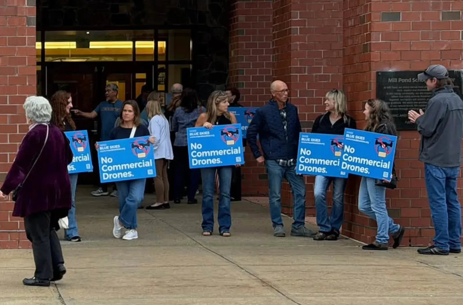 Residents holding Mass Blue Skies signs outside Mill Pond School before the Select Board meeting on October 1