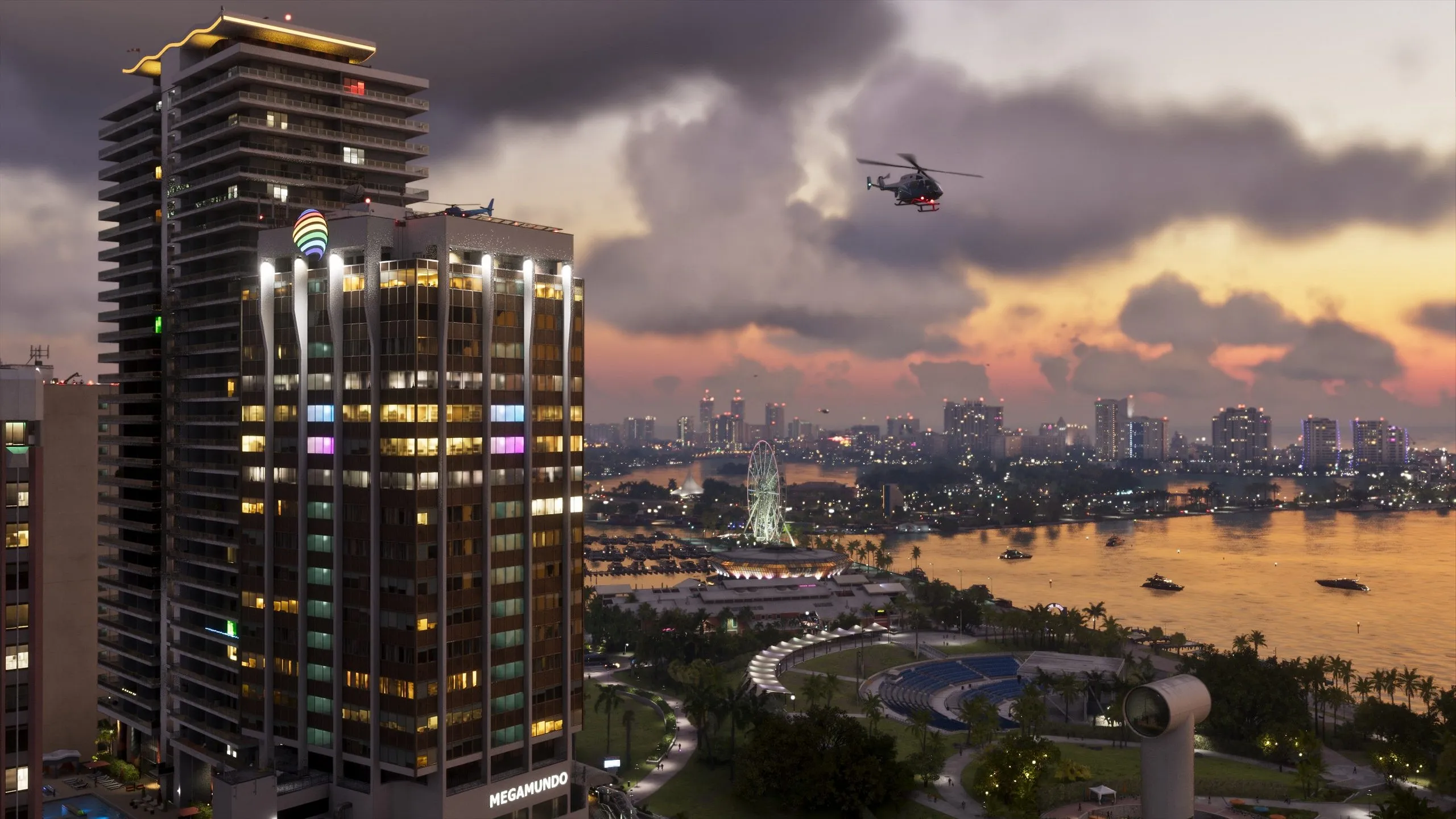 Un helicóptero sobrevuela una ciudad al atardecer con la torre MEGAMUNDO y una noria al fondo