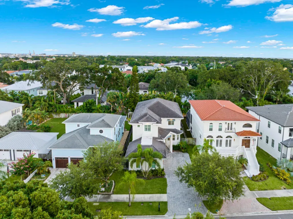 Vista aérea de una vivienda de dos plantas con tejado gris y camino de entrada adoquinado entre casas vecinas de un barrio arbolado de Tampa