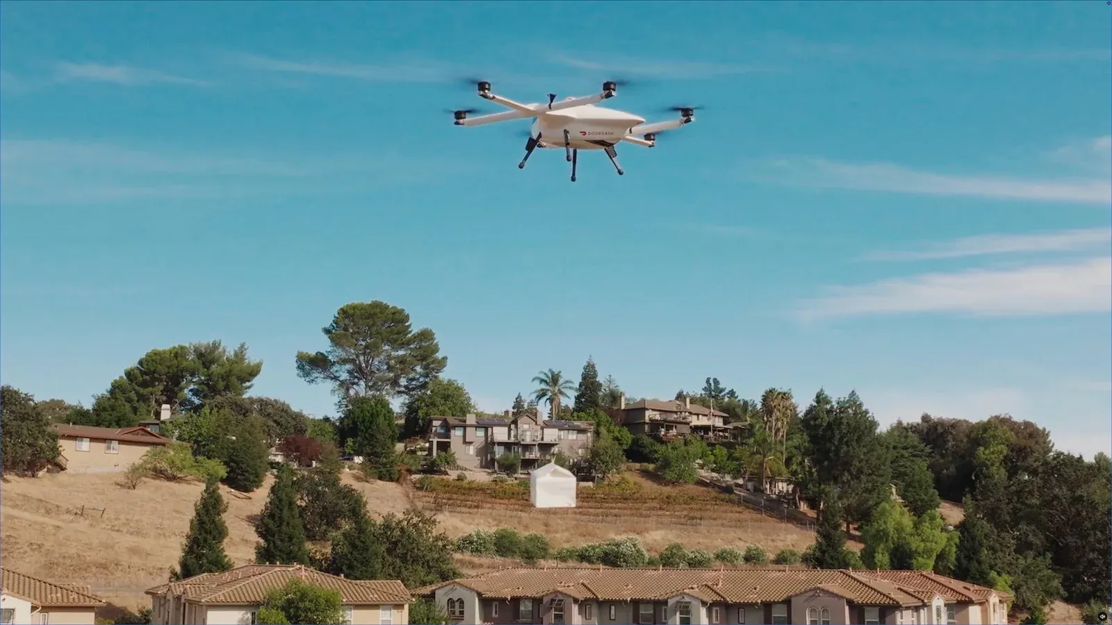 DoorDash Air drone lowering an order on its winch over a residential hillside