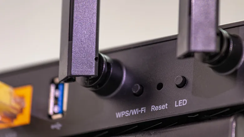 Botón WPS en la parte trasera de un router, junto al orificio de reinicio